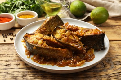 Photo of Tasty Indian fish curry on wooden table, closeup