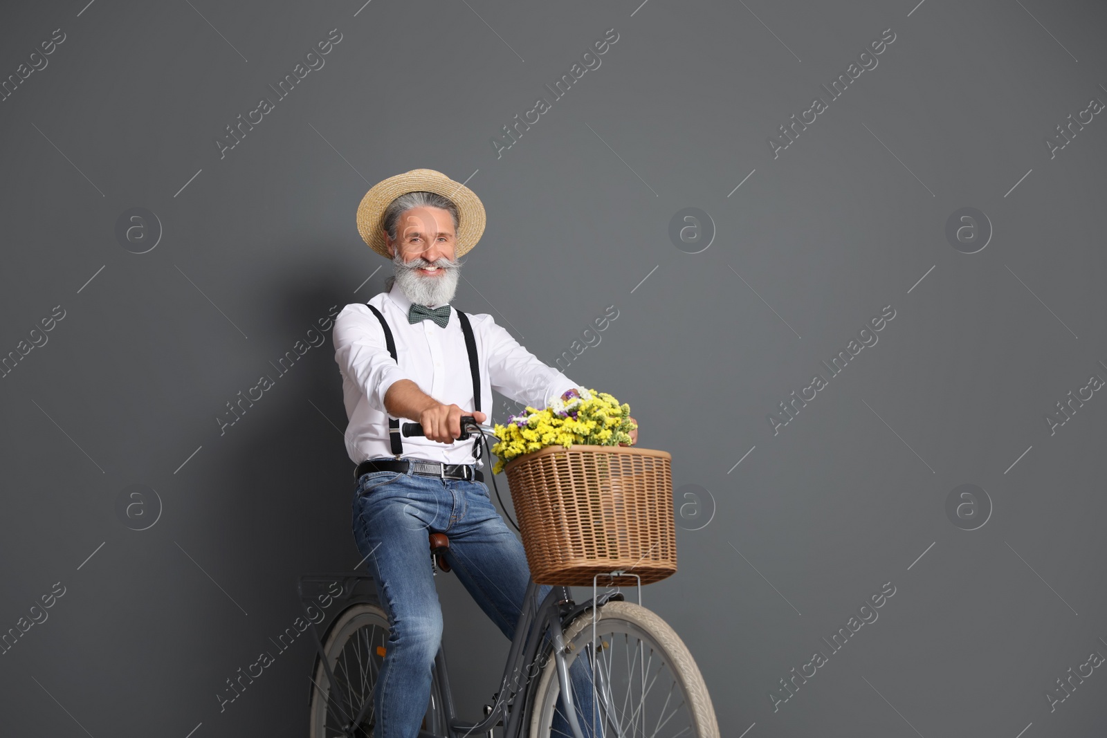 Photo of Portrait of handsome mature man with bicycle on color background