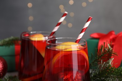 Photo of Christmas Sangria drink in glasses and fir branches against blurred lights, closeup