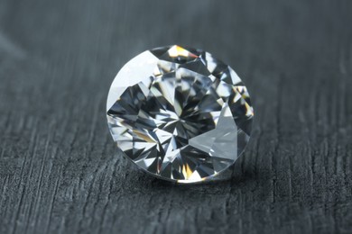 Photo of Beautiful shiny diamond on dark gray table, closeup