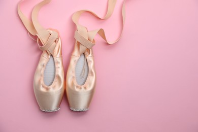Photo of Ballet shoes. Elegant pointes on pink background, flat lay. Space for text