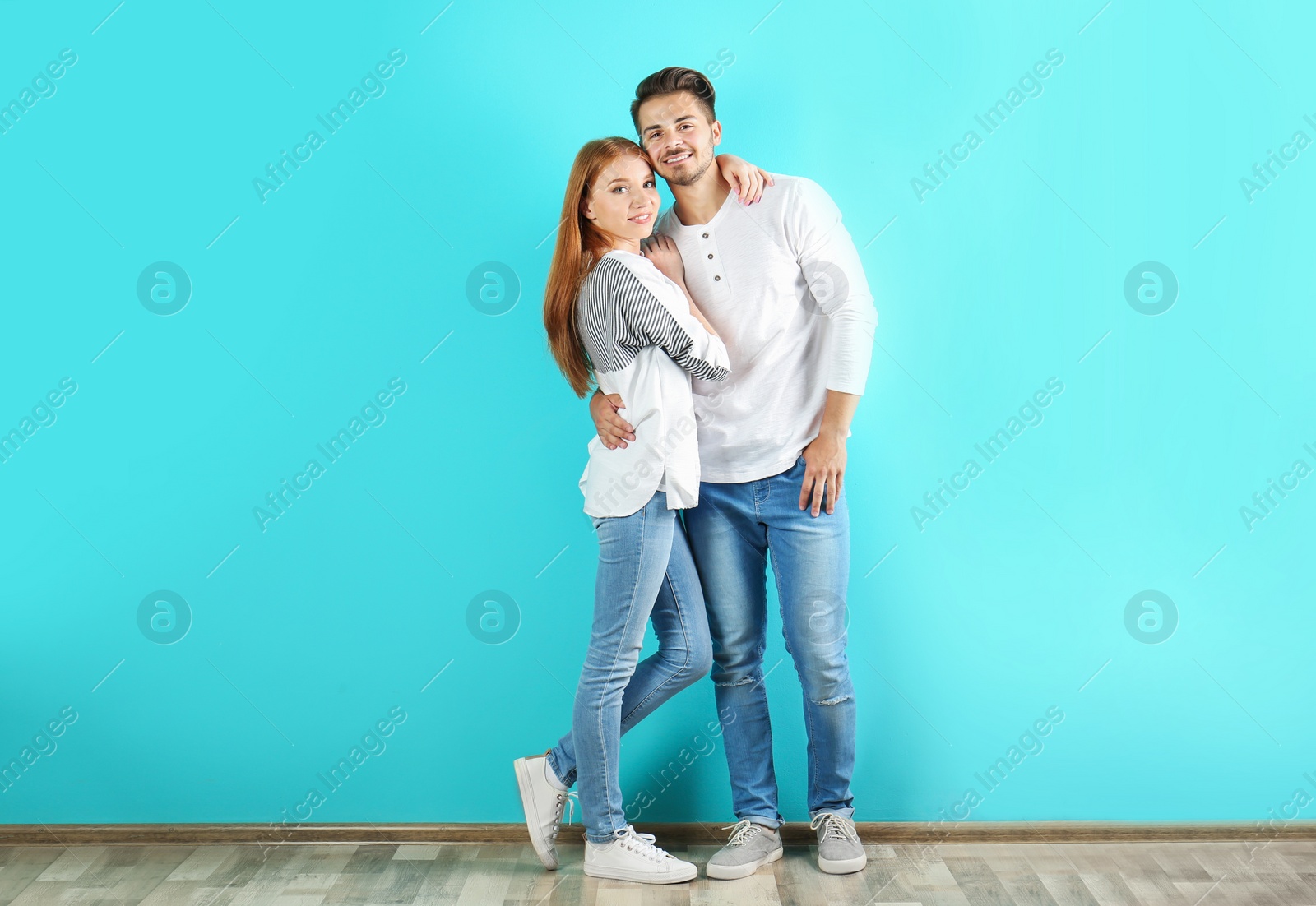 Photo of Young couple in stylish jeans near color wall