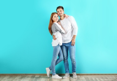 Photo of Young couple in stylish jeans near color wall