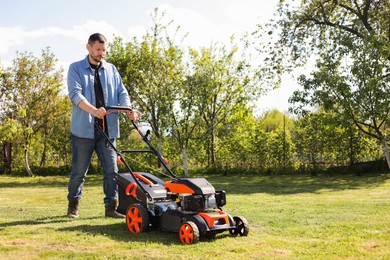 Man cutting green grass with lawn mower in garden