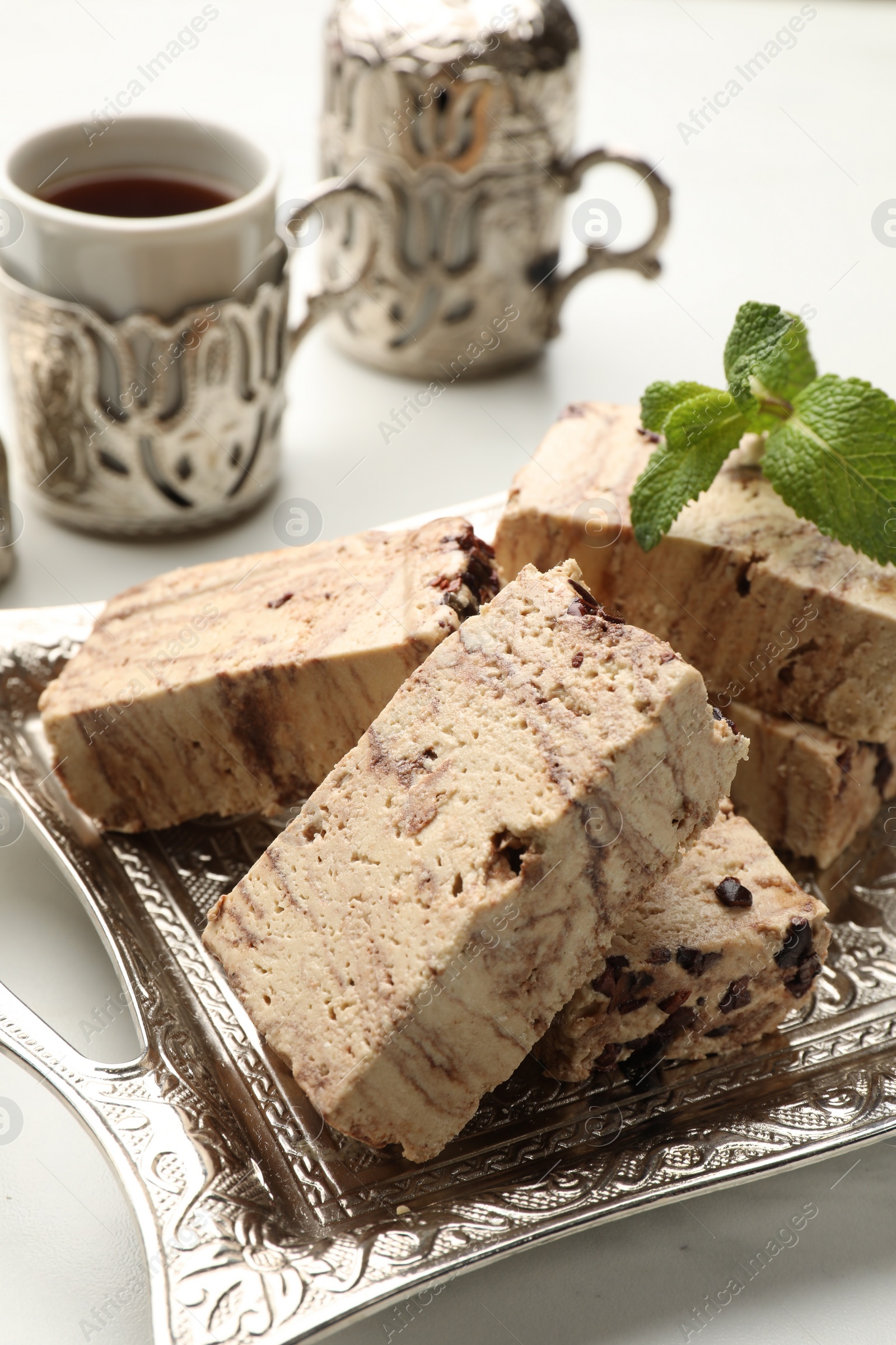 Photo of Tasty chocolate halva and mint on white marble table