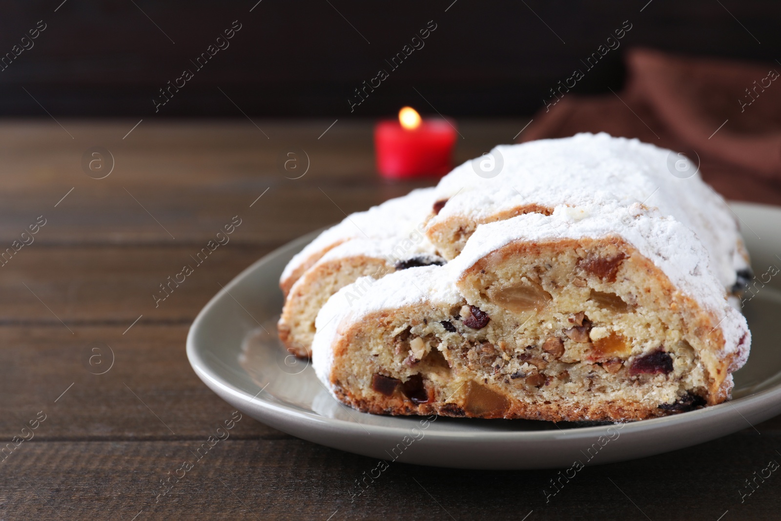 Photo of Traditional Christmas Stollen with icing sugar on wooden table