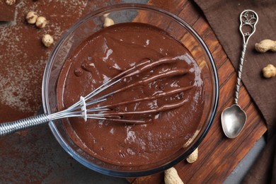 Photo of Bowl of chocolate cream, whisk and spoon on table, above view