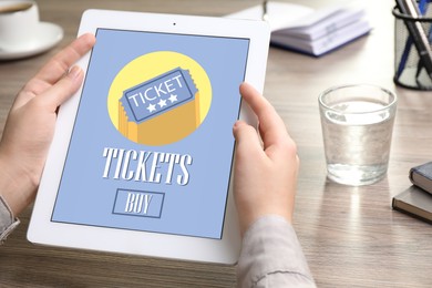 Woman buying tickets online via tablet at table, closeup