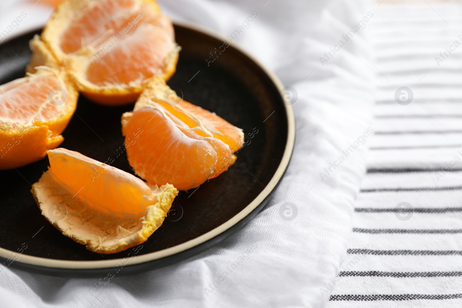 Photo of Fresh ripe tangerines on striped cloth, closeup. Space for text