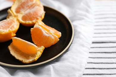 Fresh ripe tangerines on striped cloth, closeup. Space for text