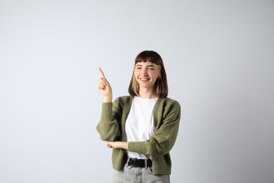 Beautiful young girl pointing on white background