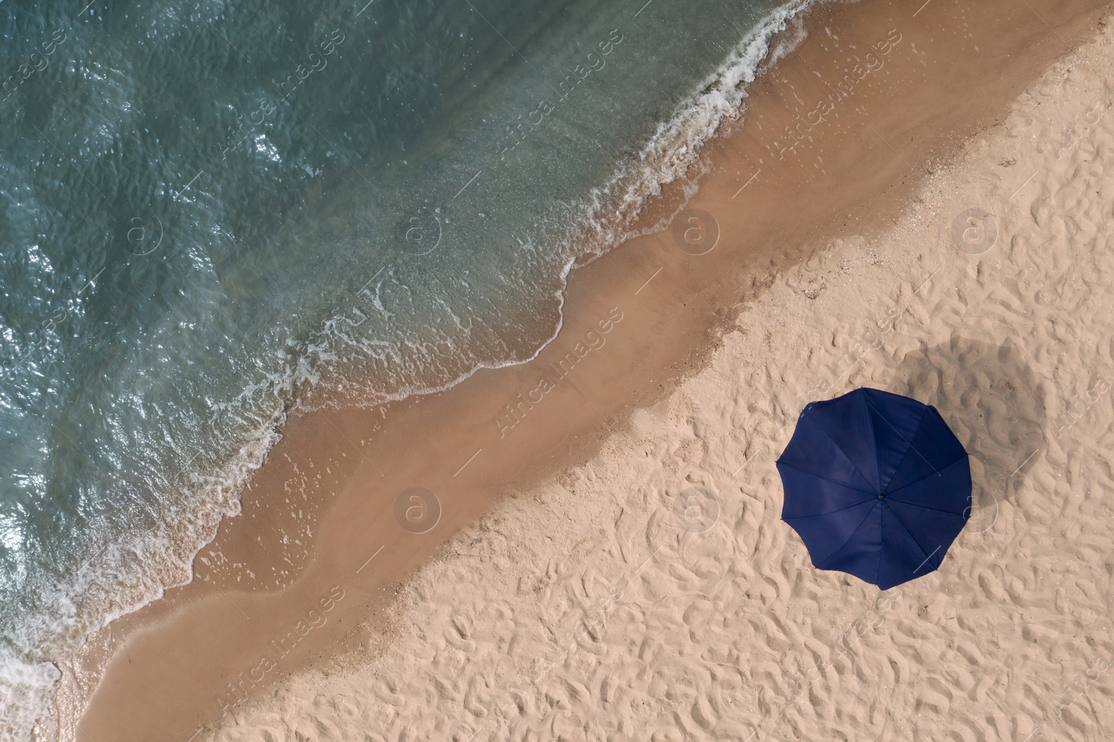 Image of Beach umbrella on sandy coast near sea, top view