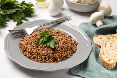 Photo of Tasty buckwheat with fresh parsley served on white tiled table