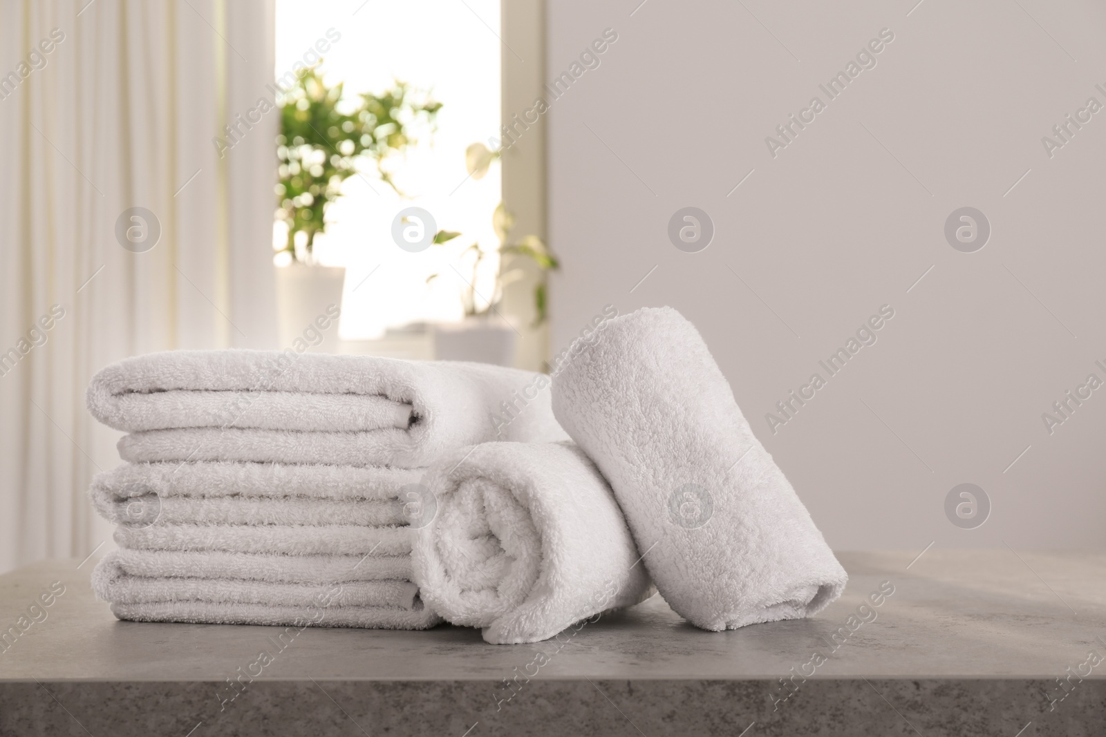 Photo of Fresh towels on light grey stone table in bathroom