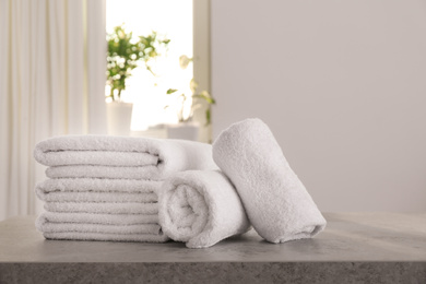 Photo of Fresh towels on light grey stone table in bathroom