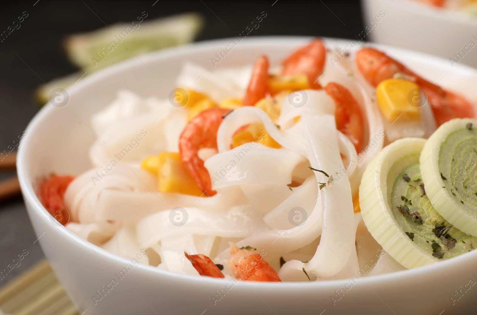 Photo of Bowl with rice noodles, shrimps and vegetables, closeup