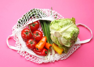 String bag with different vegetables on bright pink background, top view