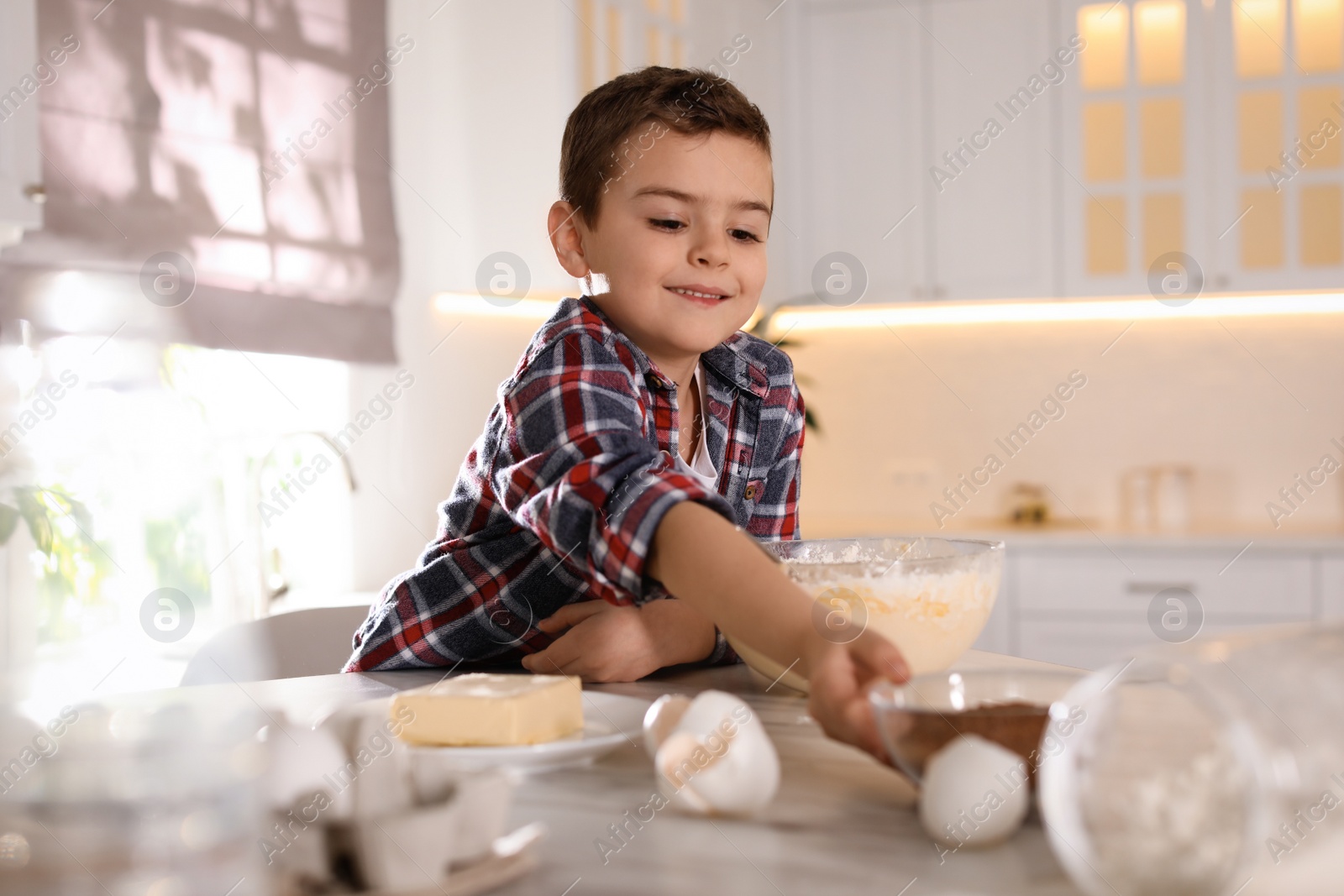 Photo of Cute little boy cooking dough in kitchen at home