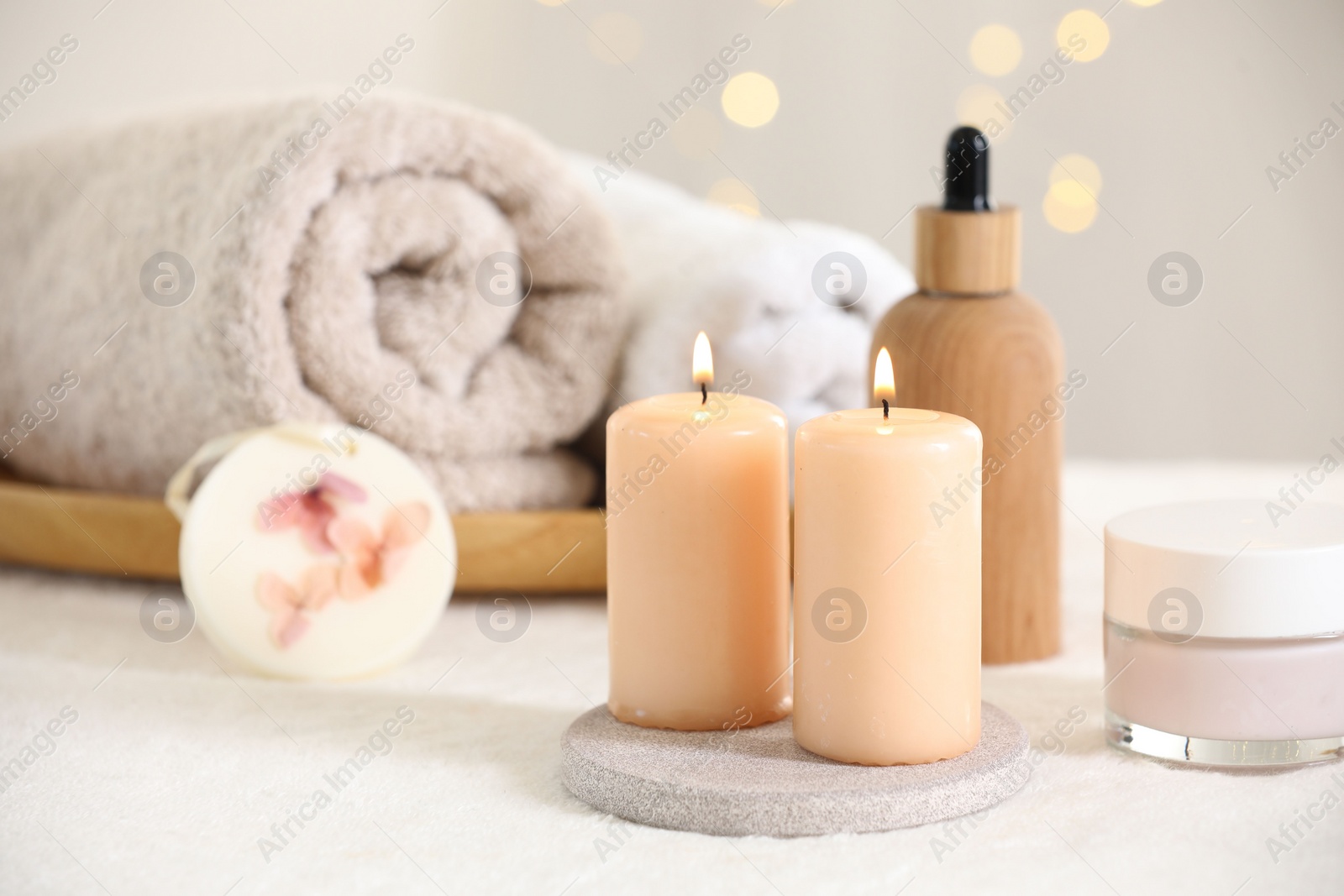 Photo of Spa composition. Burning candles and personal care products on soft white surface