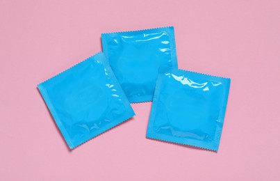 Photo of Condom packages on pink background, flat lay. Safe sex