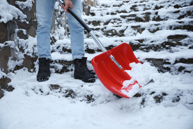 Photo of Man cleaning stairs from snow with shovel outdoors on winter day, closeup