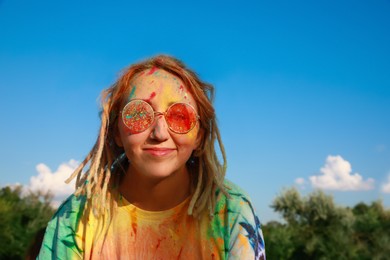 Photo of Happy woman covered with colorful powder dyes outdoors. Holi festival celebration