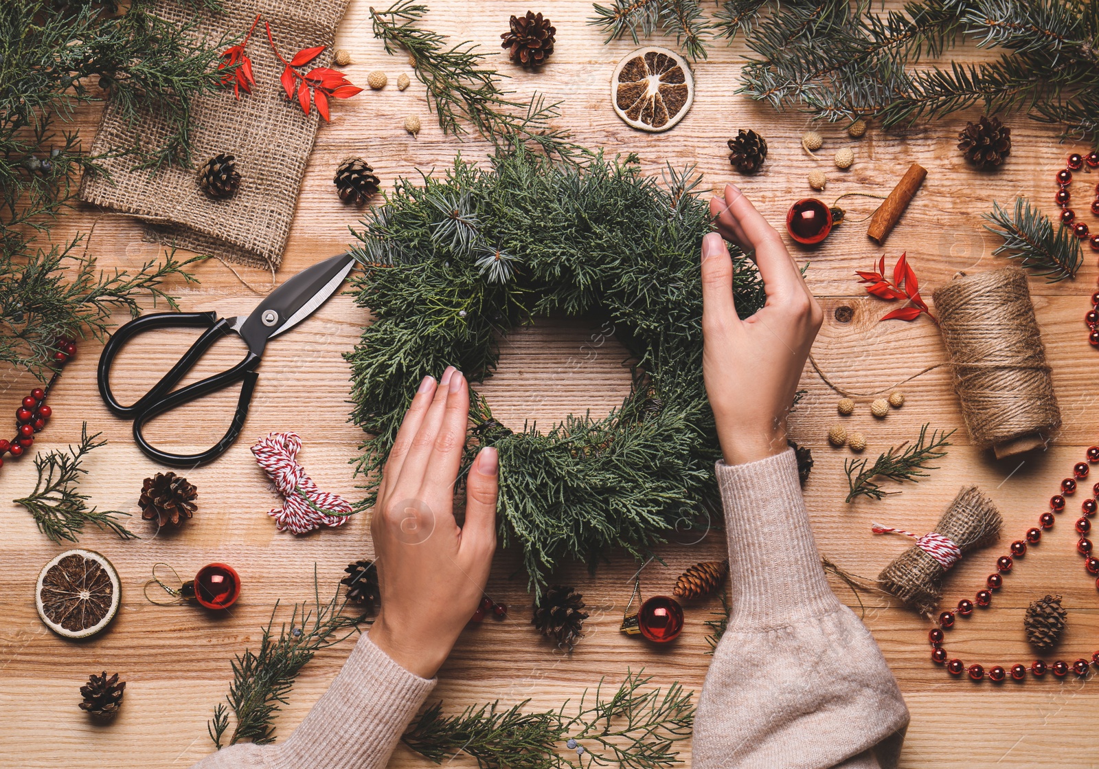 Photo of Florist making beautiful Christmas wreath at wooden table, top view