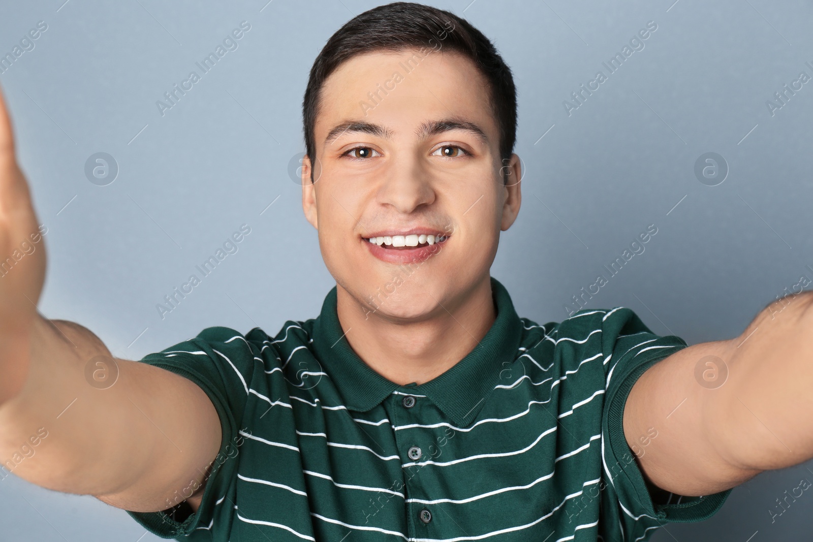 Photo of Young handsome man taking selfie against grey background