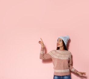 Photo of Young woman in warm sweater and knitted hat on color background. Christmas celebration