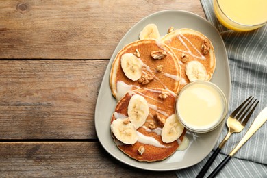 Tasty pancakes with sliced banana served on wooden table, flat lay. Space for text