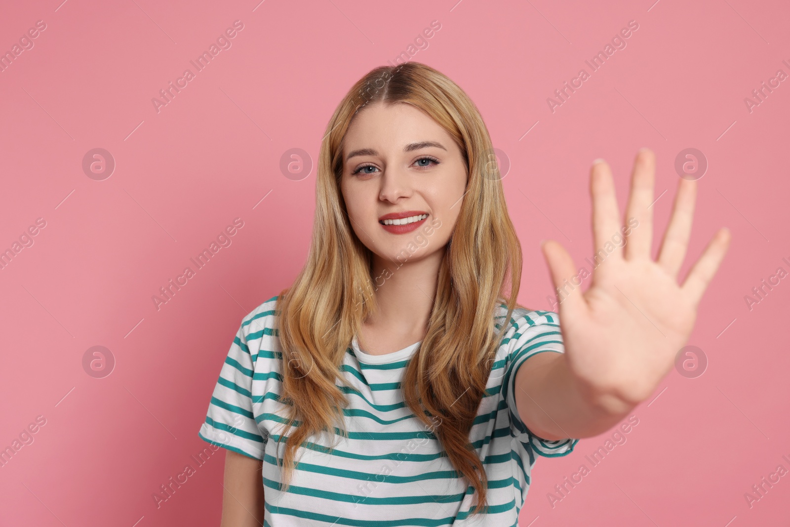 Photo of Happy woman giving high five on pink background