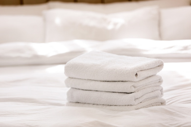 Stack of fresh towels on bed indoors