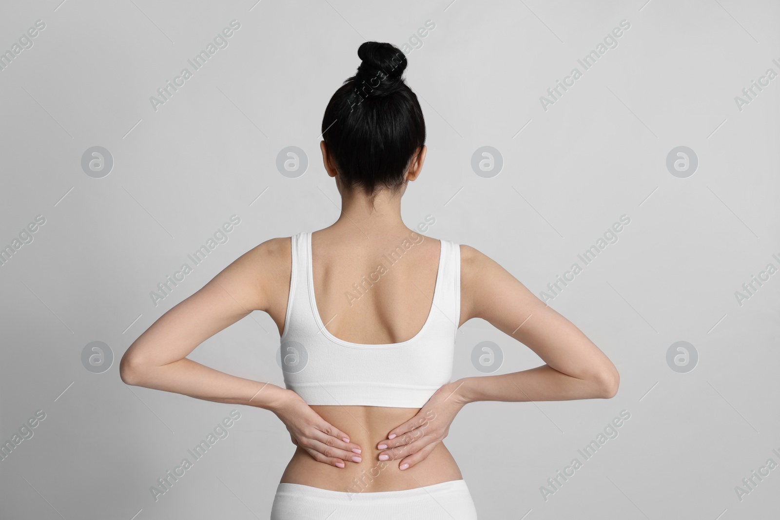 Photo of Woman suffering from pain in back on light background