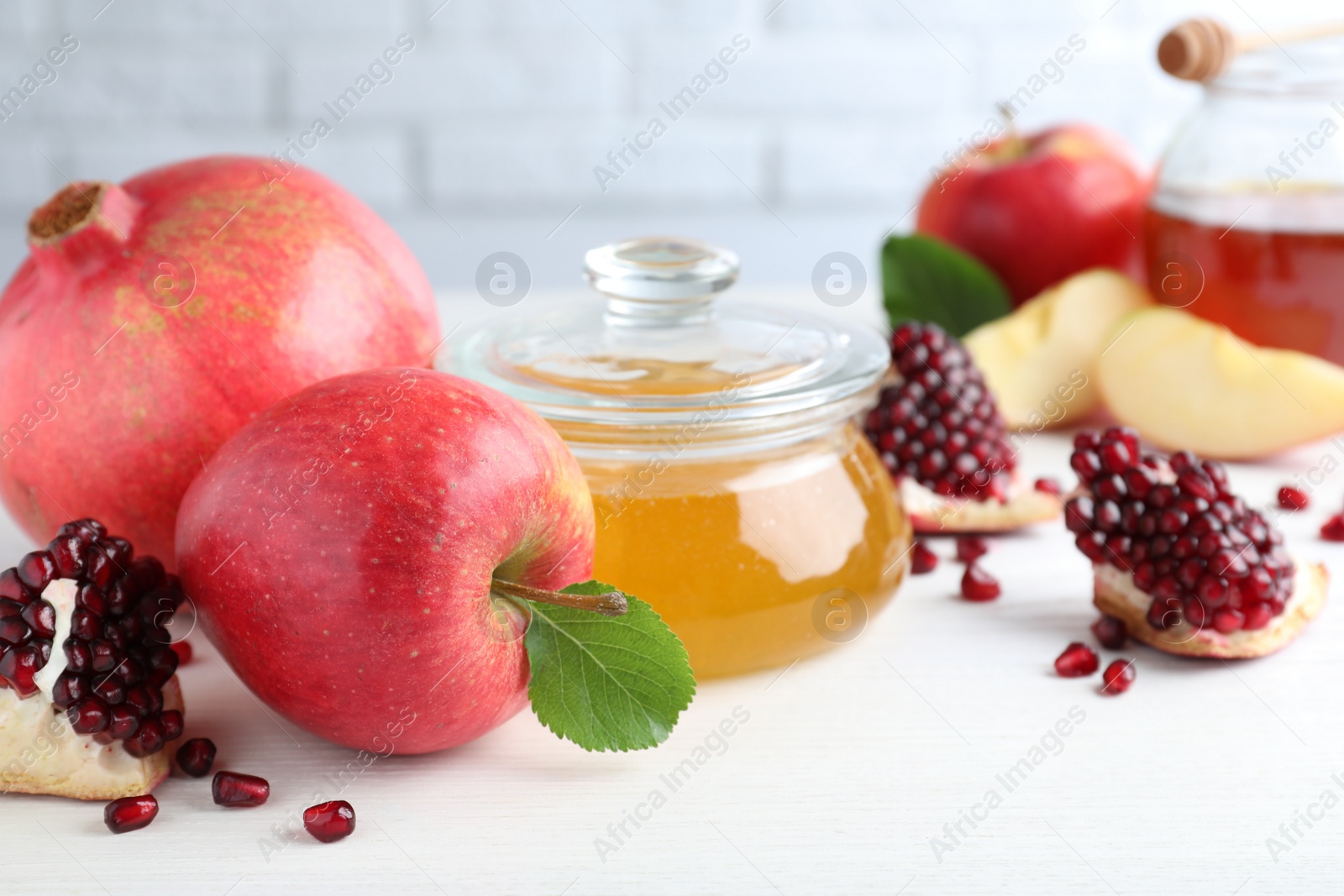 Photo of Honey, pomegranate and apples on white wooden table, closeup. Rosh Hashana holiday