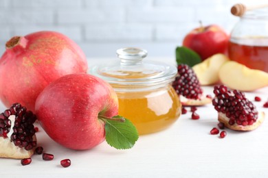 Honey, pomegranate and apples on white wooden table, closeup. Rosh Hashana holiday