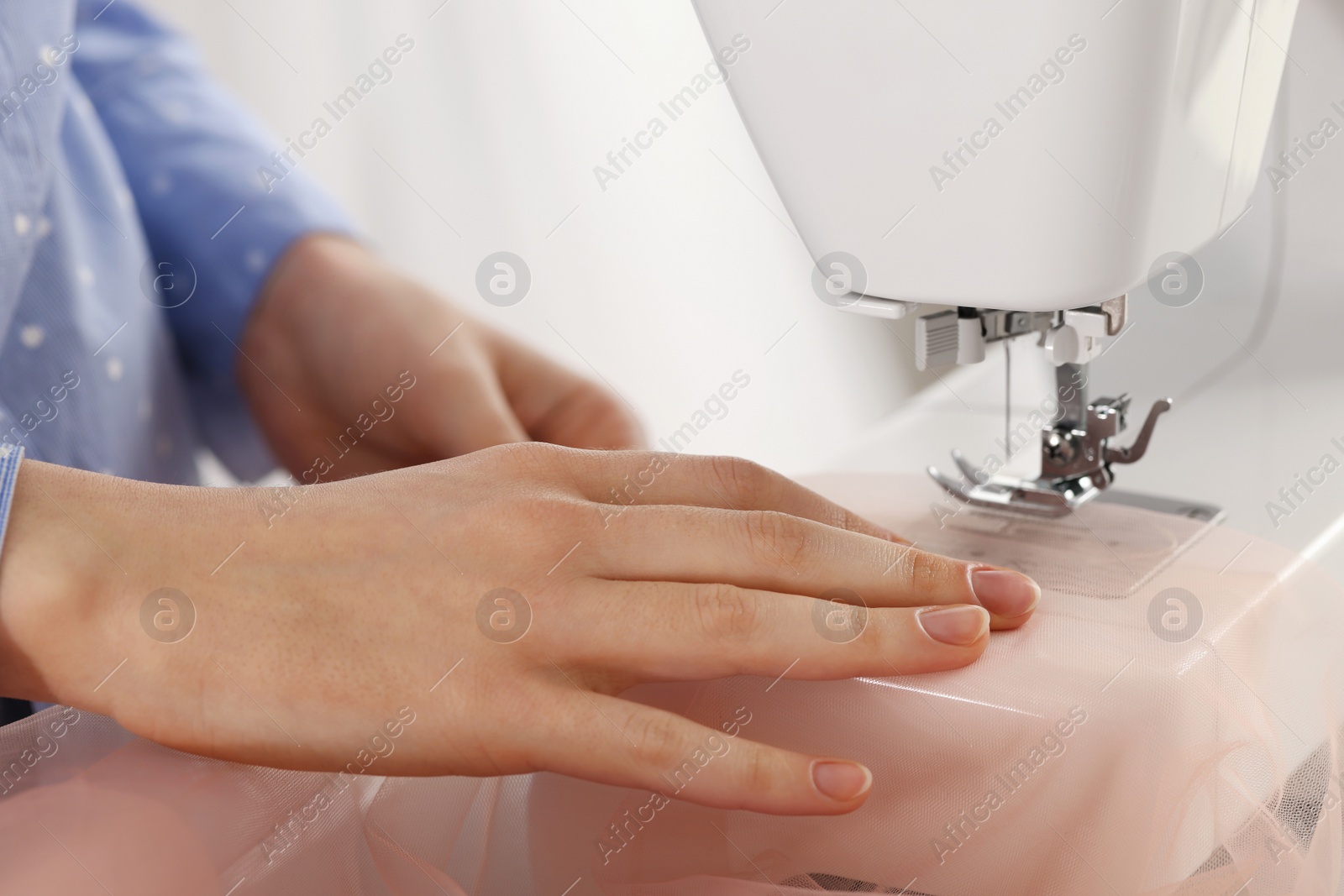 Photo of Dressmaker sewing new dress with machine in atelier, closeup