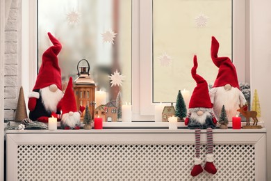 Photo of Cute Christmas gnomes and other festive decorations on windowsill in room