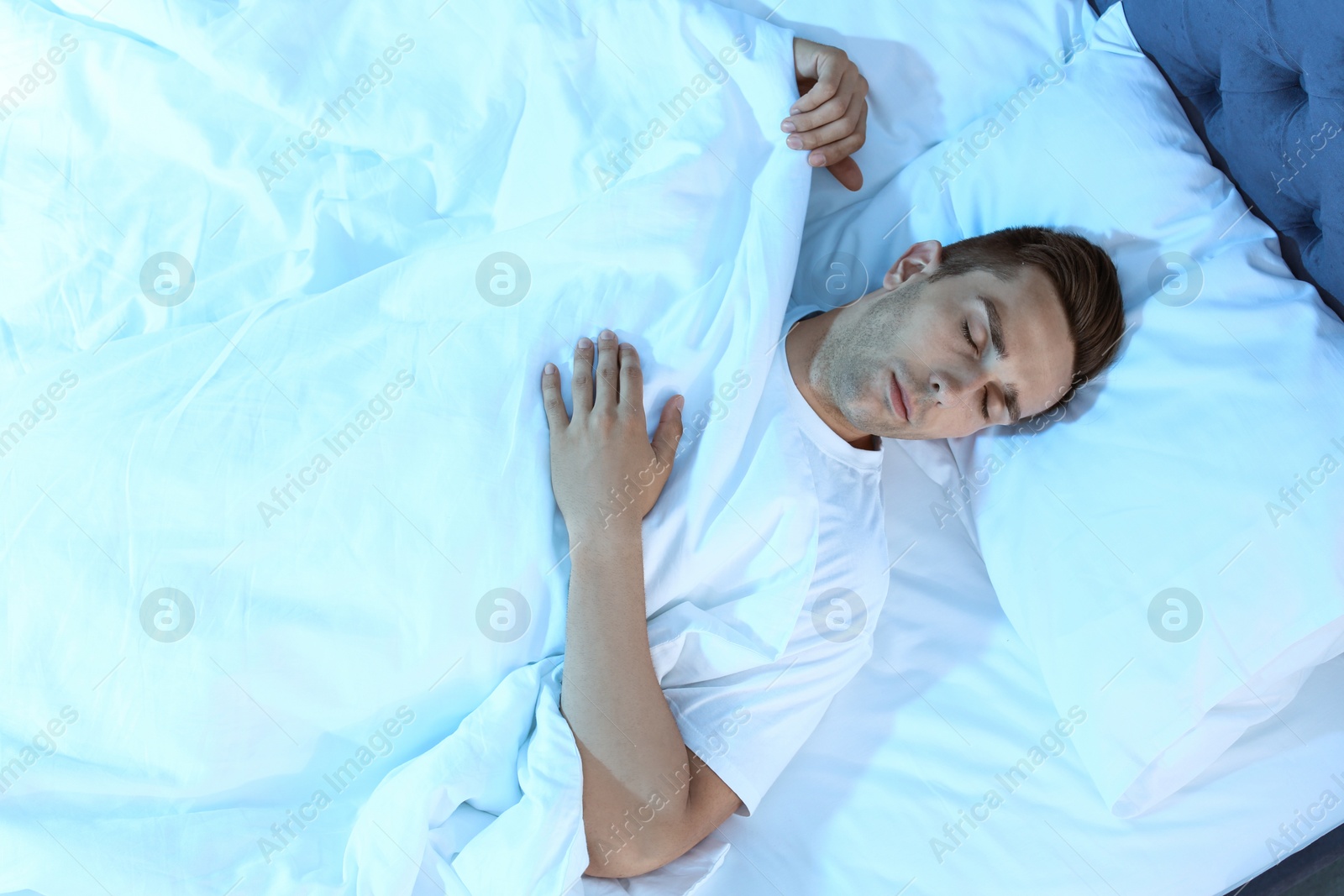 Photo of Young man sleeping in bed at night, top view