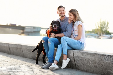 Photo of Cute brown labrador retriever with owners outdoors