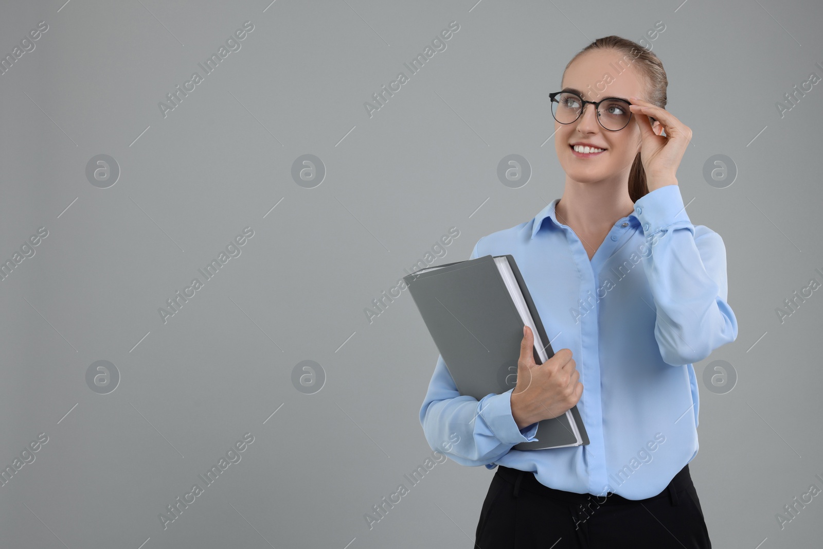 Photo of Happy young secretary with folder on grey background, space for text