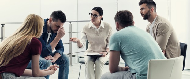 Image of Psychotherapist working with group of drug addicted people at therapy session indoors. Banner design