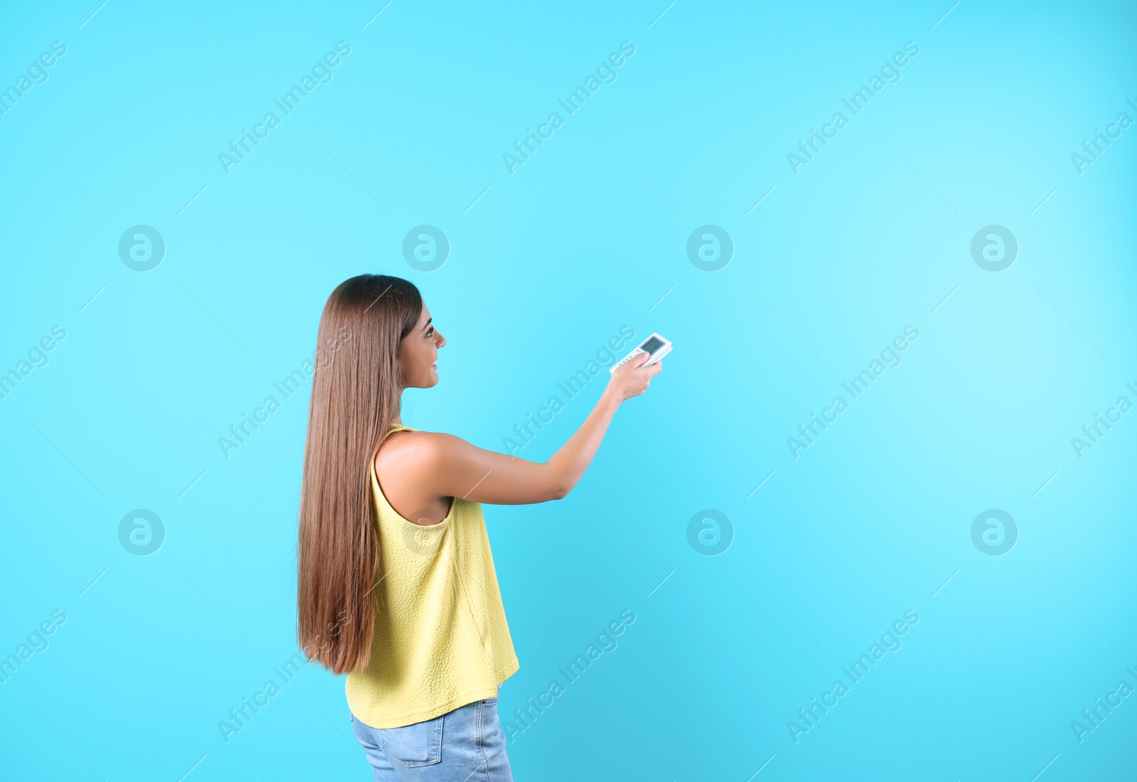 Photo of Young woman with air conditioner remote on color background, copy space text