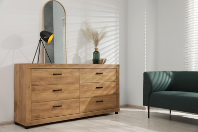 New wooden chest of drawers near sofa in stylish room
