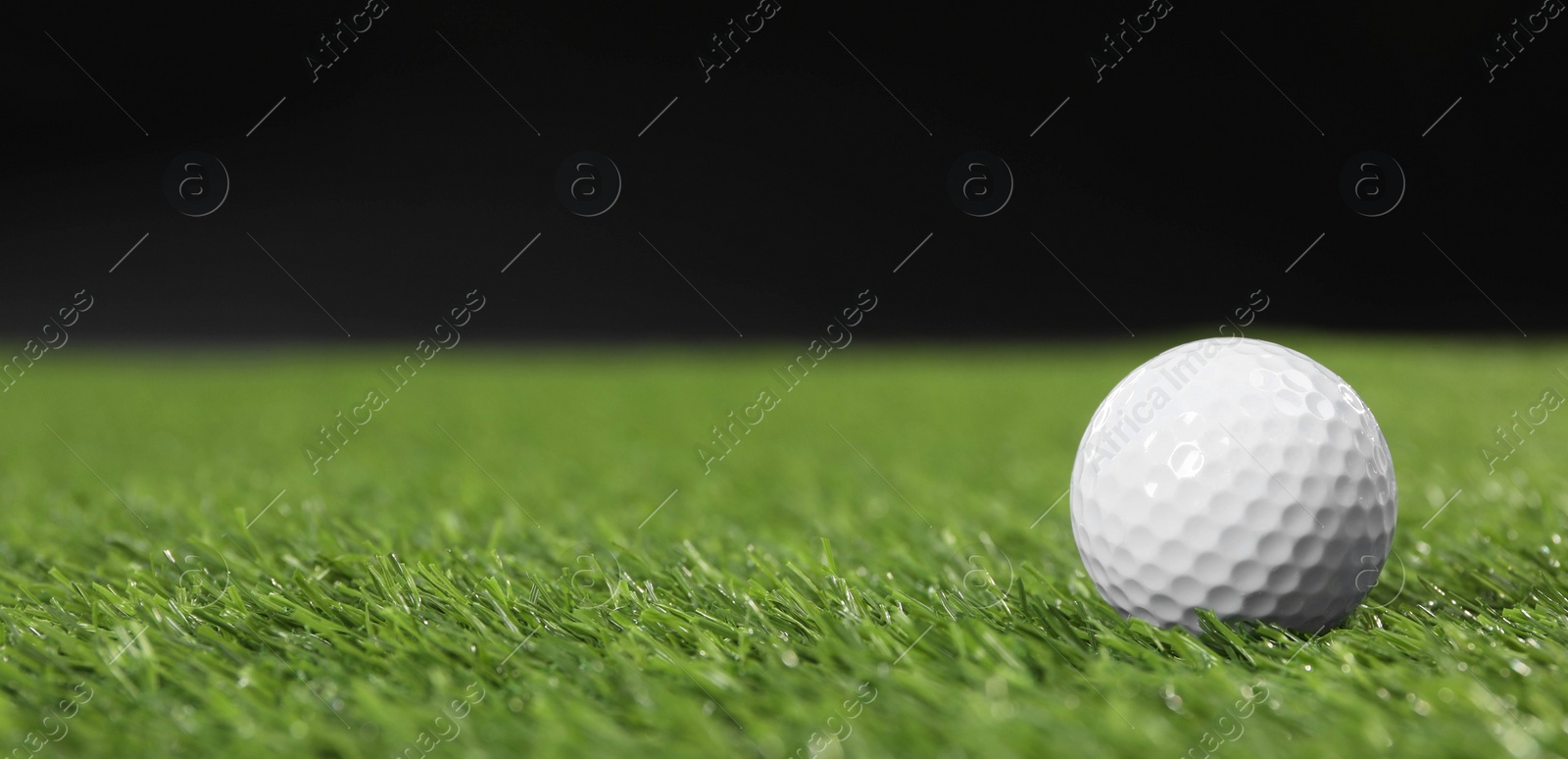 Photo of Golf ball on green grass against black background, space for text. Banner design