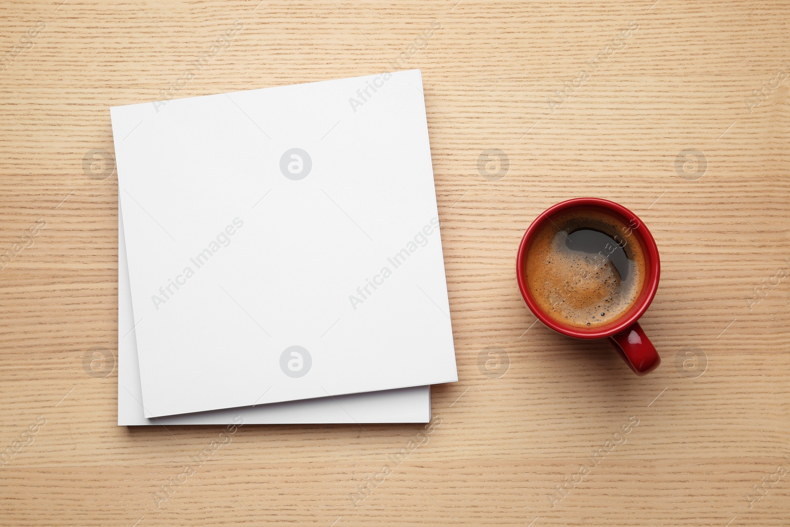 Photo of Blank paper sheets for brochure and cup of coffee on wooden background, flat lay. Mock up