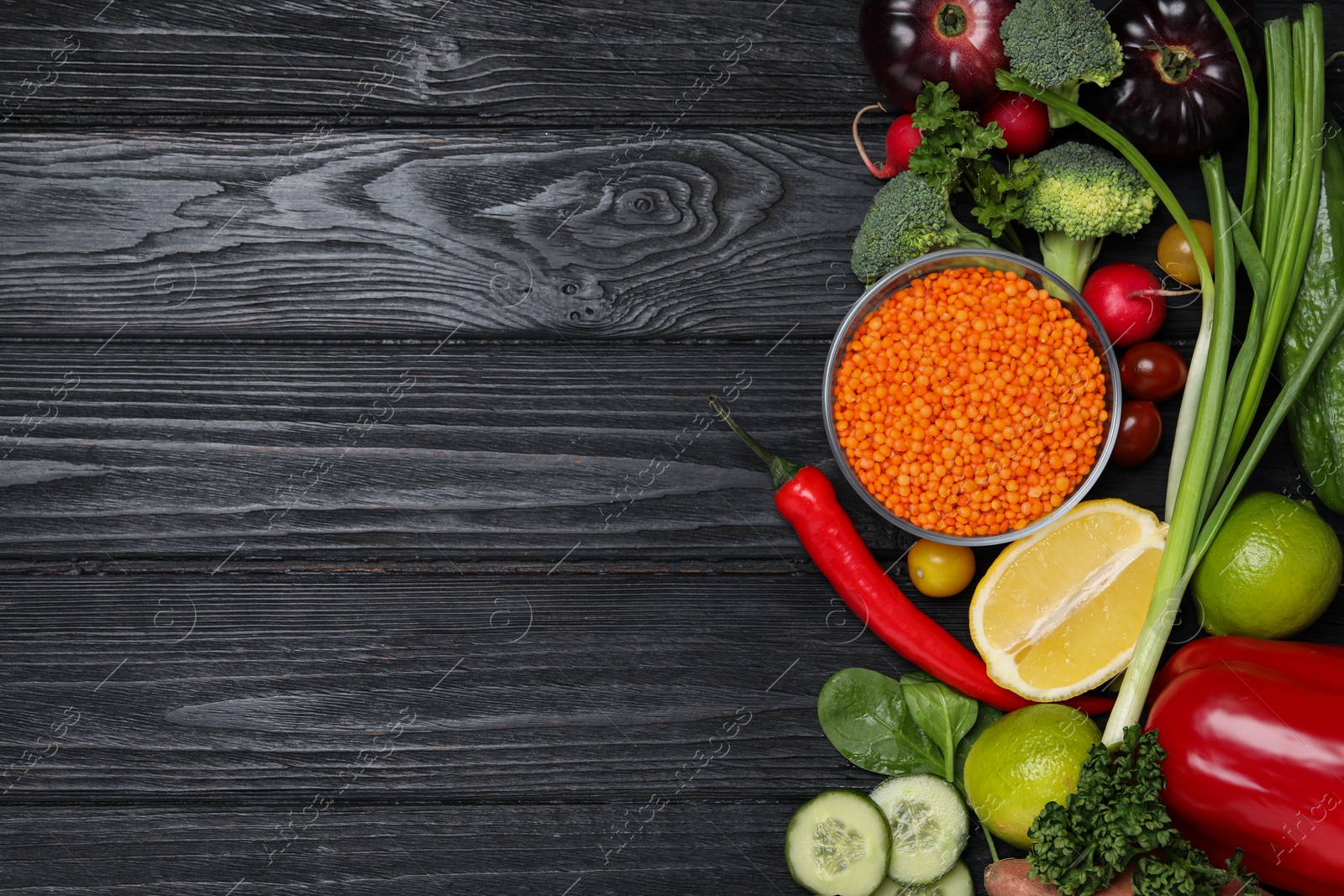 Photo of Different vegetables on black wooden table, flat lay with space for text. Vegan diet