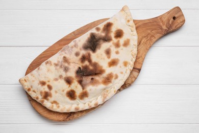 Delicious calzone on white wooden table, top view