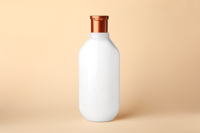 Photo of One bottle of shampoo on beige background