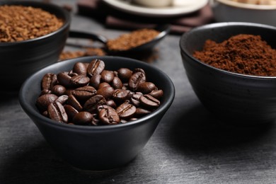 Photo of Bowls of beans, instant and ground coffee on grey table, closeup