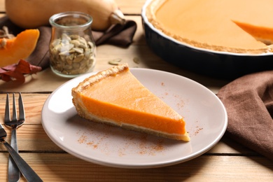 Plate with piece of fresh delicious homemade pumpkin pie on wooden table